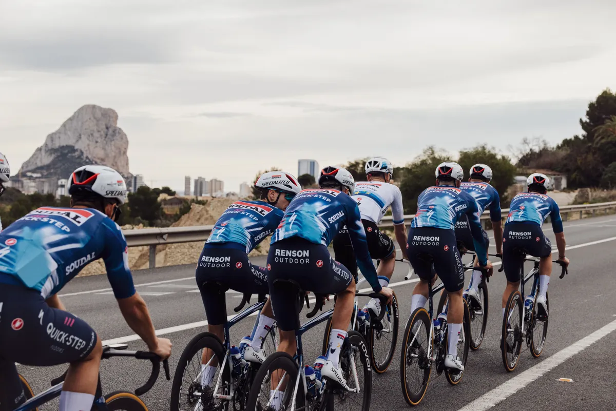 Soudal Quick-step pro cycling team riding in Calpe with Peñon de Ifach on the background