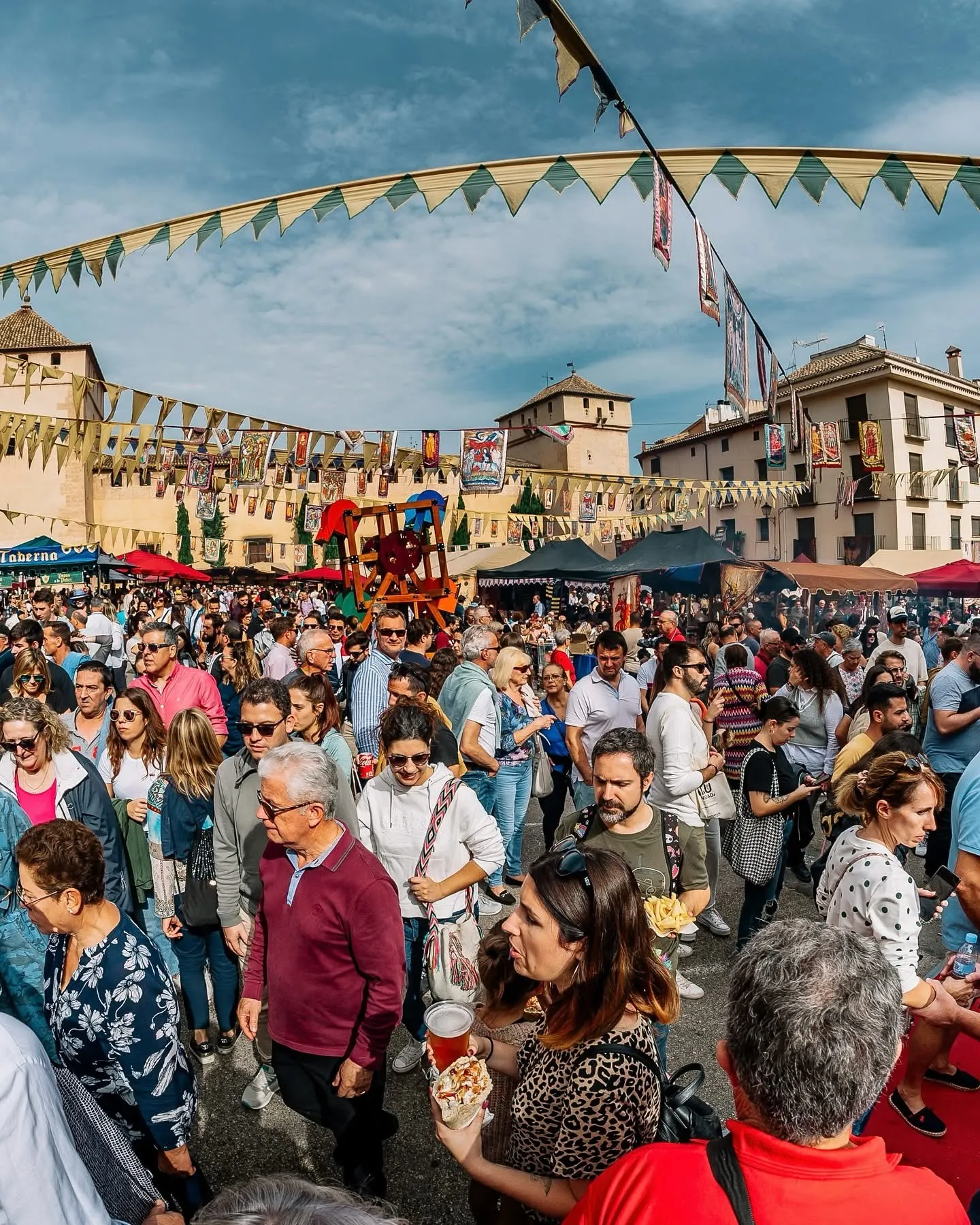 Crowds Enjoying the Fira de Tots Sants in Cocentaina A large crowd fills the main street of Cocentaina during the Fira de Tots Sants, with flags and market stalls creating a festive atmosphere.