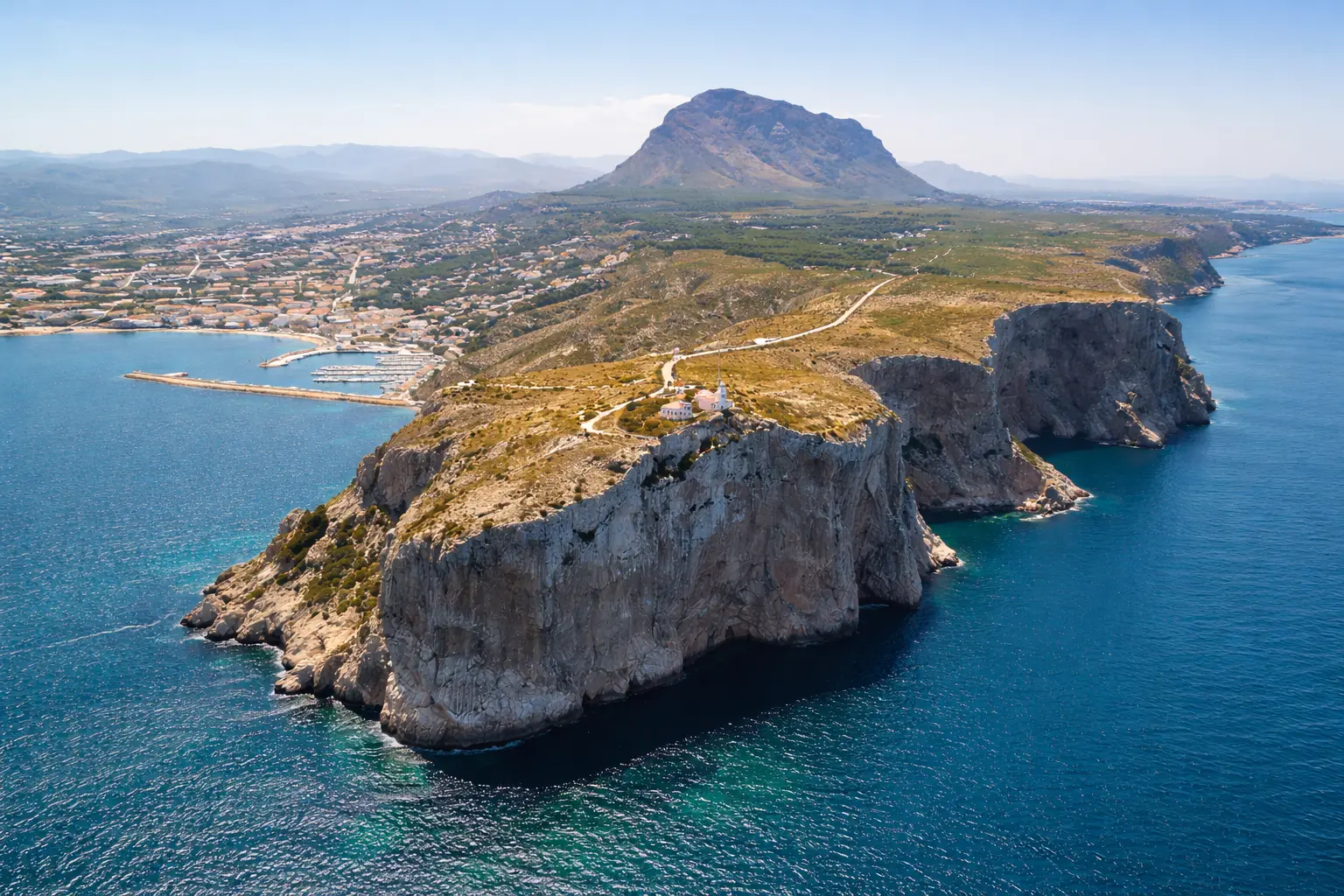 Serra Gelada Natural Park Cliffs and Albir Lighthouse with Montgó in the Background Aerial view of Serra Gelada cliffs and Albir lighthouse on the Costa Blanca with the Montgó mountain in the distance
